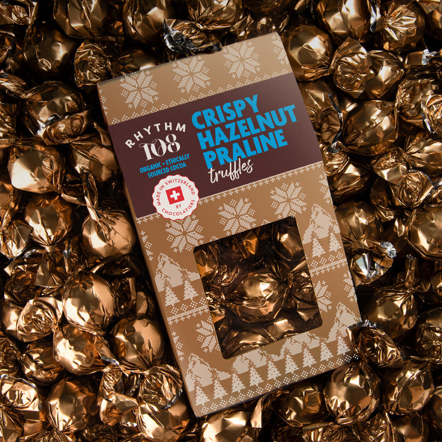 Box of Rhythm of Crispy Hazelnut Praline truffles surrounded by gold wrappers.